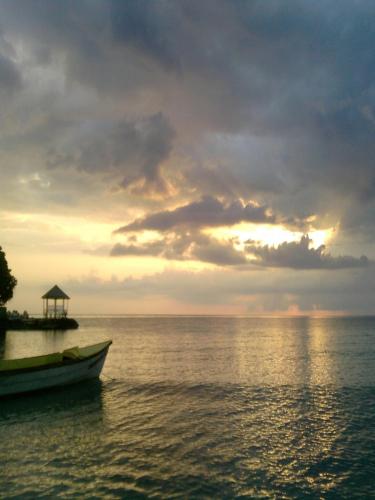 a boat on the water under a cloudy sky at Shades Cottage Guesthouse in Blue Hole