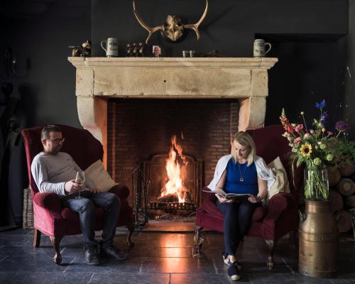 two people sitting in chairs in front of a fireplace at Hotel De Kruishoeve 's-Hertogenbosch - Vught in Vught