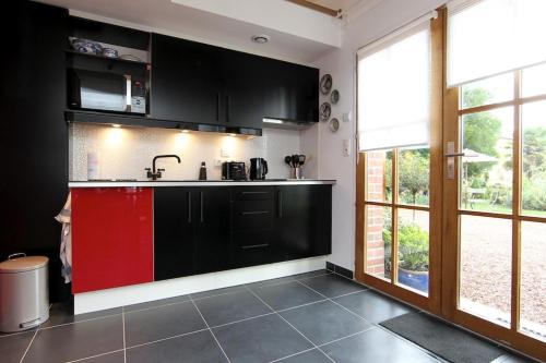 a kitchen with black cabinets and a red refrigerator at Comme une parenthèse au coeur des hortillonnages in Amiens