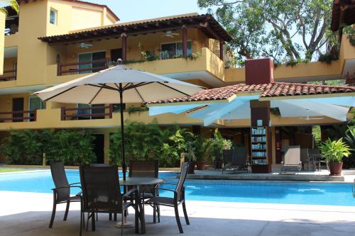 a table and chairs with an umbrella next to a pool at Los Mangos in Zihuatanejo
