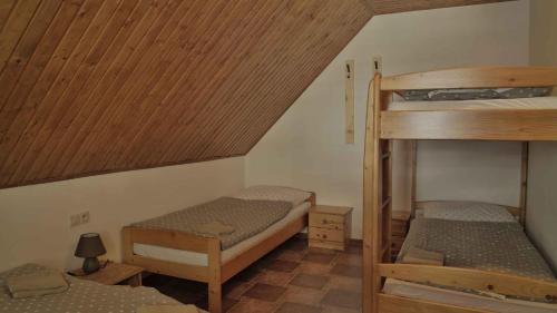 a room with two bunk beds and a wooden ceiling at Penzion Ostruznik in Ostružná