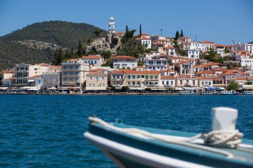 a boat in the water with a town in the background at Hotel Saron in Poros