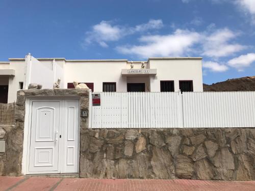 una casa blanca detrás de una pared de piedra con una puerta en Lancelot, en Puerto Rico de Gran Canaria