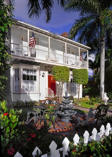 a white house with an american flag and a fountain at Sabal Palm House Bed and Breakfast in Lake Worth