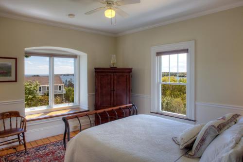 a bedroom with a bed and two windows at Harbor House Inn in Boothbay Harbor