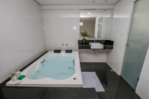 a bathroom with a jacuzzi tub and a sink at Hotel Nacional in João Monlevade