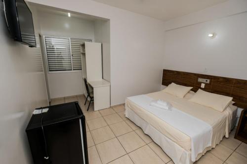 a bedroom with a bed and a television in it at Hotel Nacional in João Monlevade