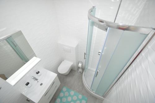 a white bathroom with a shower and a sink at Apartments Silvia in Zadar
