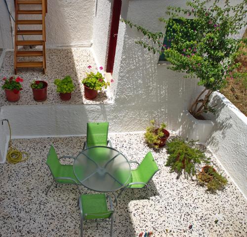 a patio with a table and chairs and plants at Nikos Rooms in Votsi