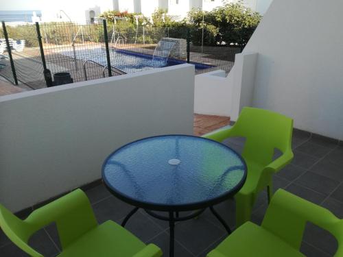 a blue table and green chairs on a balcony at Mda Playa del Cantal in Mojácar
