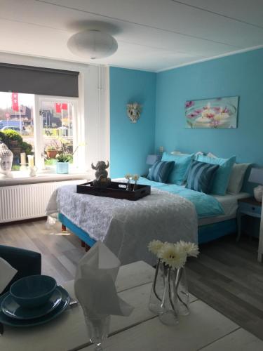 um quarto azul com uma cama e um sofá em Huize de Weijde Blick em Wijk aan Zee