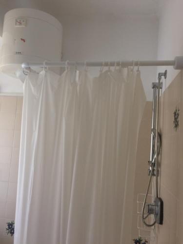 a white shower curtain hanging in a bathroom at Appartamento in Alassio Centro a 5 minuti dal Mare in Alassio