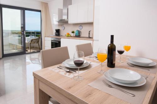 a dining table with wine glasses and a bottle of wine at Aparthotel Punta Blu - POOL & SPA in Premantura