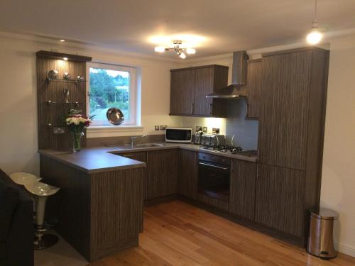 een keuken met houten kasten en een aanrechtblad bij The Botanic Hub West End - 2 Bedrooms in Glasgow