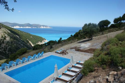 a pool with chairs and the ocean in the background at Myrtos Bay Apartments in Anomeriá