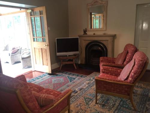 uma sala de estar com duas cadeiras e uma televisão em Creevy Lodge em Castlederg