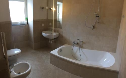 a bathroom with a toilet and a tub and a sink at Harbour View B&B in Ischia