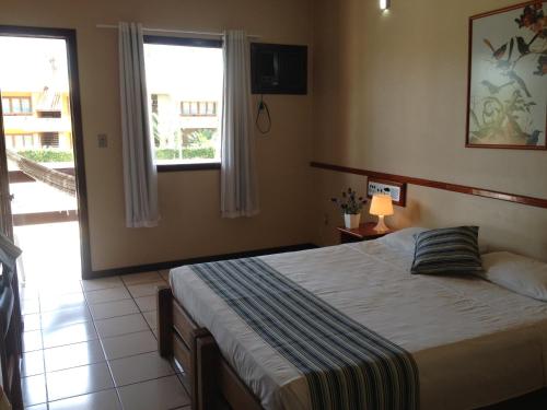 1 dormitorio con cama y ventana en Taperapuan Praia Hotel, en Porto Seguro