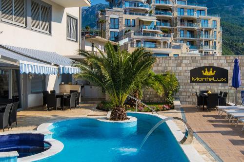 a swimming pool with a palm tree in front of a building at Montelux Apartments in Budva