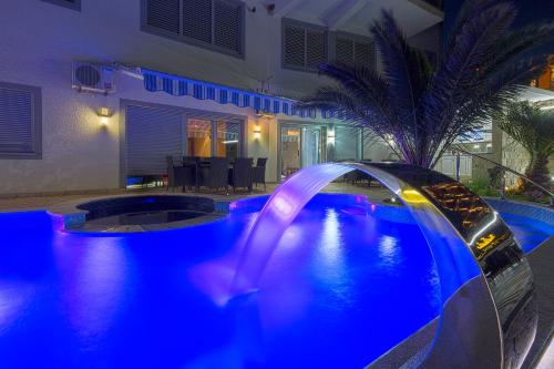 a pool with a water slide in a backyard at night at Montelux Apartments in Budva