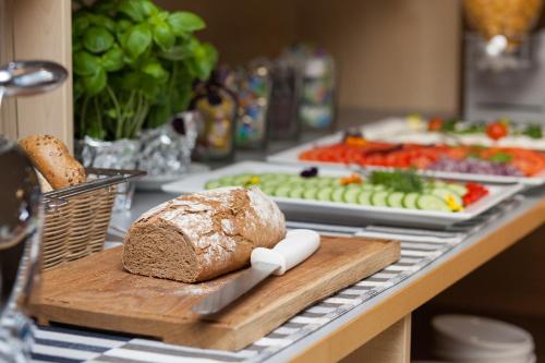 a loaf of bread on a wooden cutting board on a table with food at Hotel Perła in Kraków