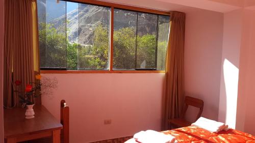a bedroom with a window and a bed and a table at Tambo de Ollantay Hotel in Ollantaytambo