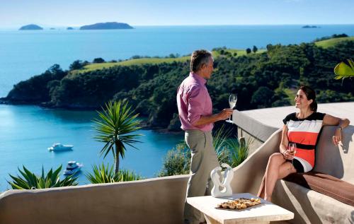 a man and woman standing on a balcony with a glass of wine at Delamore Lodge in Oneroa