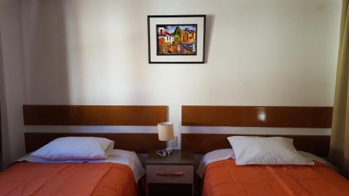 a bedroom with two beds and a picture on the wall at Tambo de Ollantay Hotel in Ollantaytambo
