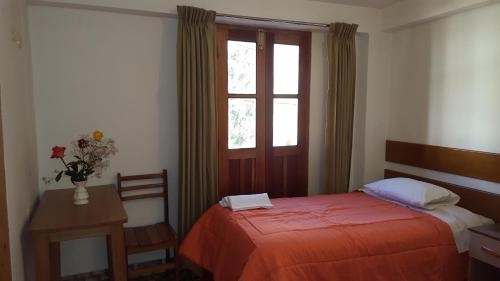 a bedroom with a bed and a window and a table at Tambo de Ollantay Hotel in Ollantaytambo
