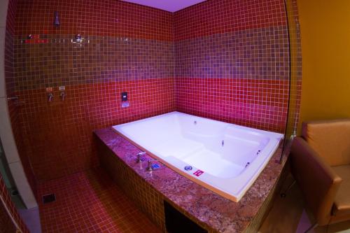 baño de azulejos rojos con bañera y pared de azulejos rojos en Platinum Motel (Adults Only) en Fortaleza