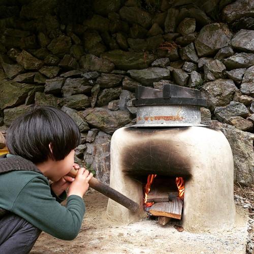 a young boy playing with a wood stove at Oyamanoyado Michitsuji in Otoyocho