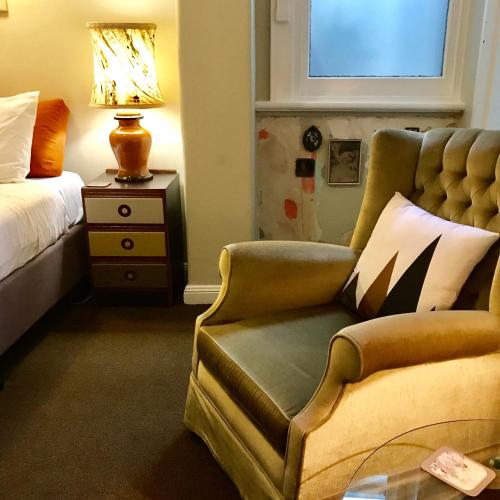 a bedroom with a couch and a bed and a lamp at Vine Valley Inn in Cessnock