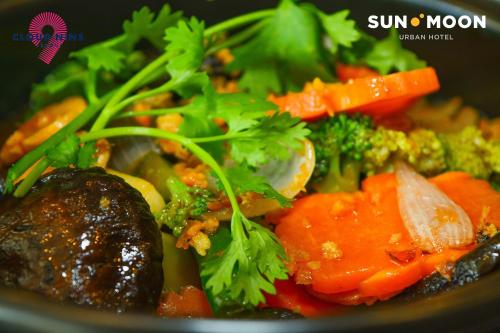 a bowl of food with broccoli carrots and other vegetables at SUN & MOON, Urban Hotel in Phnom Penh
