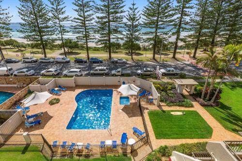 an aerial view of a pool with chairs and a parking lot at Columbia Beachfront Apartments on Rainbow Bay in Gold Coast