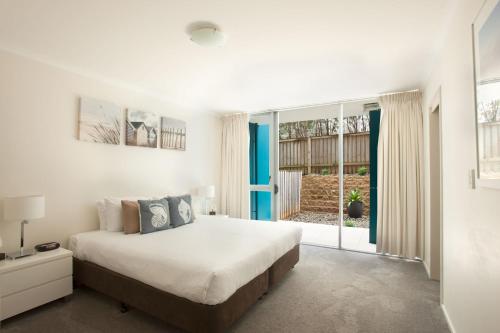 a bedroom with a bed and a large window at Ki-ea Apartments in Port Macquarie