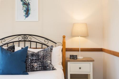 a bedroom with a bed and a night stand with a lamp at Windsors Edge Cottage Rothbury in Rothbury