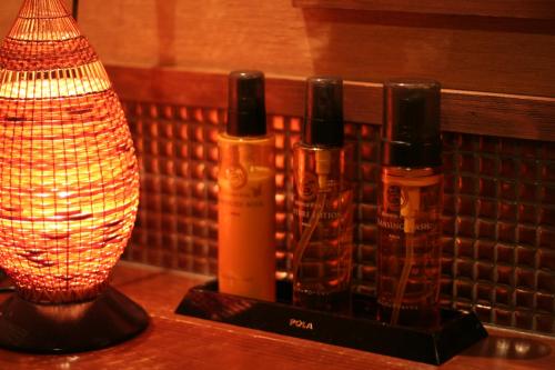 three bottles of alcohol on a table next to a lamp at Ichidaya in Toyooka