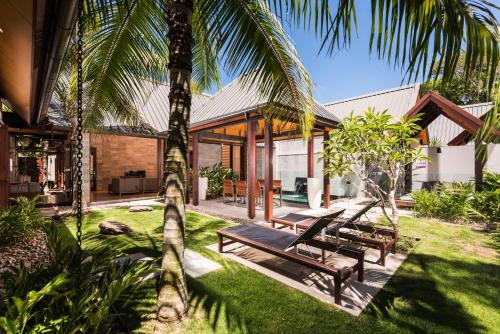 a tropical house with a hammock in the yard at Niramaya Villas and Spa in Port Douglas