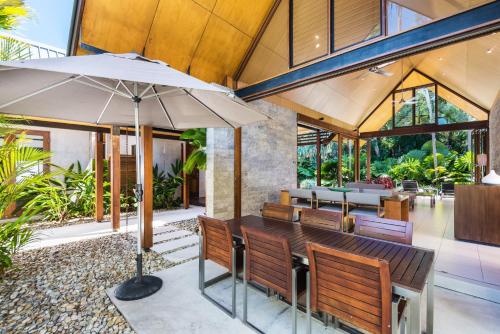 a restaurant with wooden benches and an umbrella at Niramaya Villas and Spa in Port Douglas