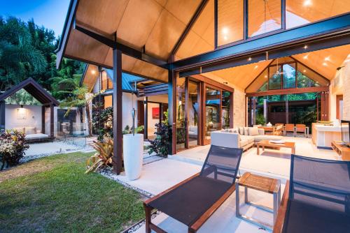 a home with a large open patio with chairs and tables at Niramaya Villas and Spa in Port Douglas