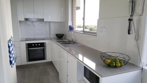a kitchen with a stove top oven and a sink at Wyuna Beachfront Holiday Apartments in Gold Coast