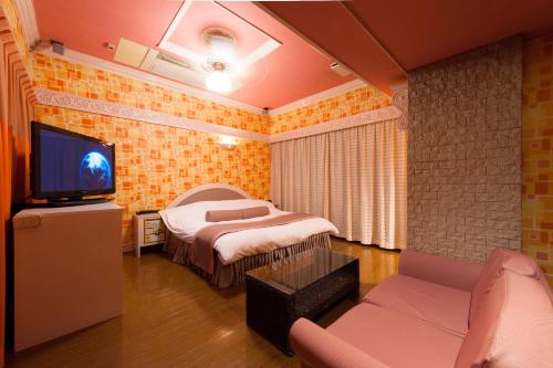 a bedroom with a bed and a tv and a couch at ホテル チャペルココナッツ 亀山 in Kameyama