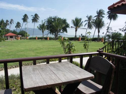 a wooden bench sitting on a balcony with a park at Sailom Resort Bangsaphan in Bang Saphan