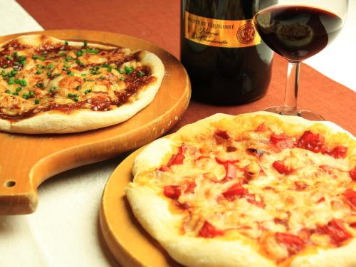 two pizzas sitting on wooden plates next to a bottle of wine at Oze Shinkousou in Katashina