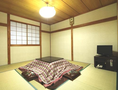 a room with a bed and a tv in it at Oze Shinkousou in Katashina