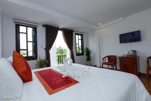 a bedroom with a white bed with a towel on it at Gia Lam Villa Hoi An in Hoi An