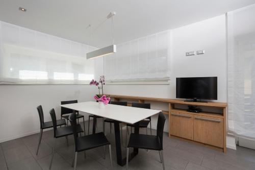 una sala da pranzo con tavolo, sedie e TV di Appartamento Mirabell ad Andalo