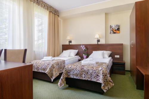 a hotel room with two beds and a table at Hotel Zielony in Poznań