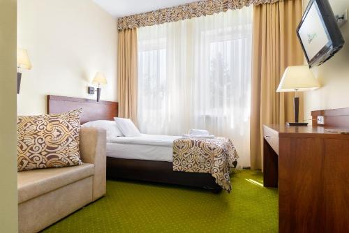 a hotel room with a bed and a chair and a television at Hotel Zielony in Poznań