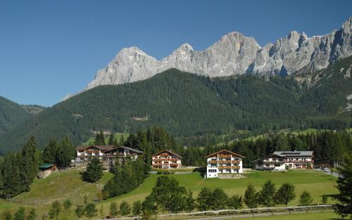 a village in the mountains with mountains in the background at Hotel Ramsaueralm in Ramsau am Dachstein